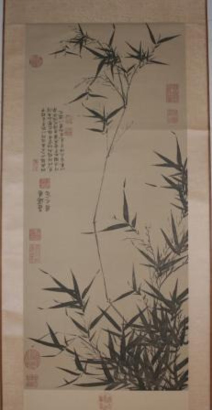 Print of dark decorative grass with Chinese characters mounted on a gold scroll.