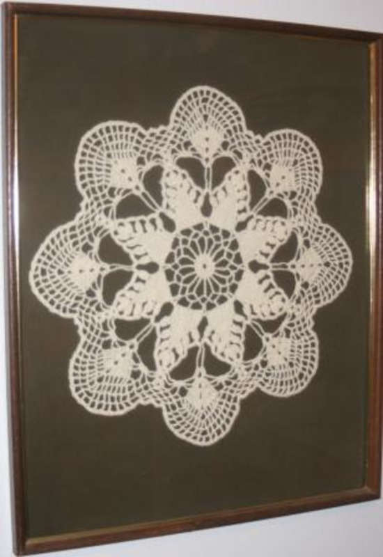 Crocheted 8 lobed pattern made from white textile mounted on a brown matte board. Purchased in Lincoln, Nebraska.