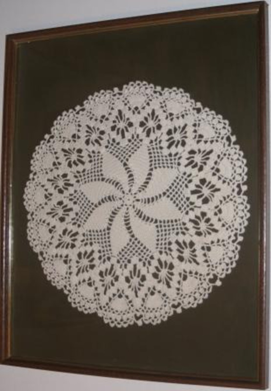 Crocheted circular pattern made from white textile mounted to a brown matte board. Purchased in Lincoln, Nebraska.