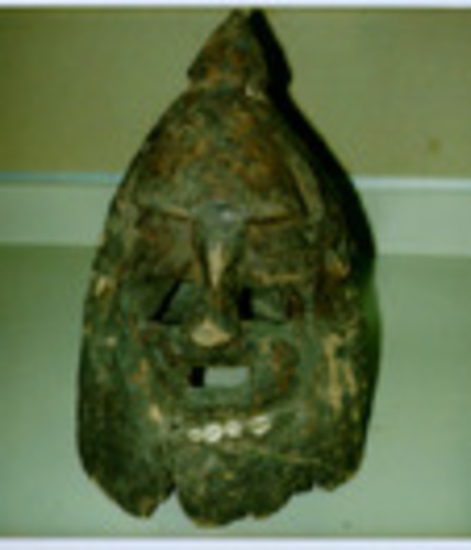 Carved wooden helmut mask with cowrie shell teeth.