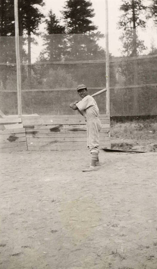 A CCC man posing with a bat over home plate.