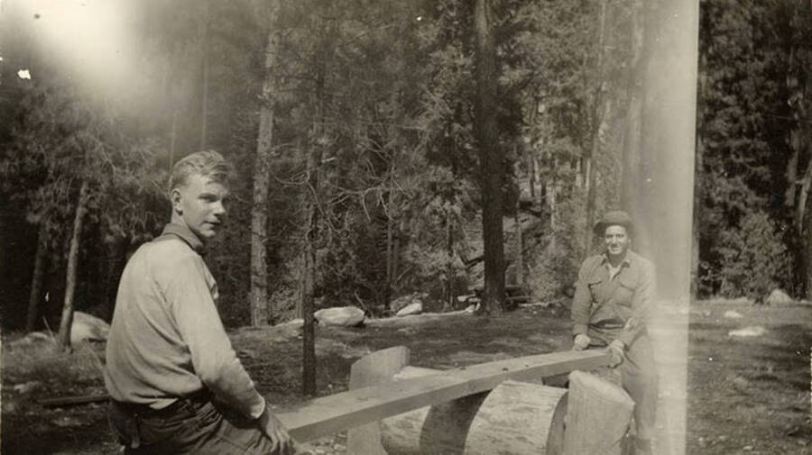 Two CCC men sitting evenly on a seesaw with the woods in the background. Writing under the photo reads: 'Me and Jake'.