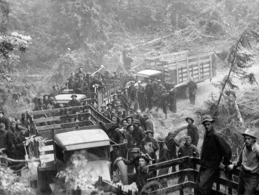 Group photo of CCC men gathered around several trucks. These men were to fight the Pack River Fire in the Kaniksu National Forest. Photo taken in August. Writing above photo reads: 'Transport to Fire - Trucks Idaho Kaniksu National Forest. CCC boys leaving trucks in the early morning for work on fire line. Pack River Fire. This is on the Kaniksu National Forest. Taken by K.D. Swan Aug. 1934.'