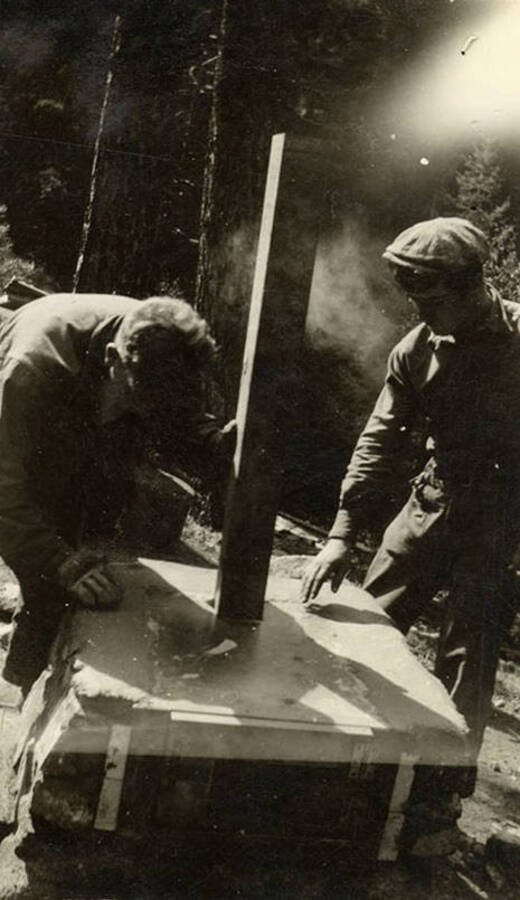 Two CCC men at work building an outdoor stove. Writing under the photo reads: 'Bubby and McMann'.