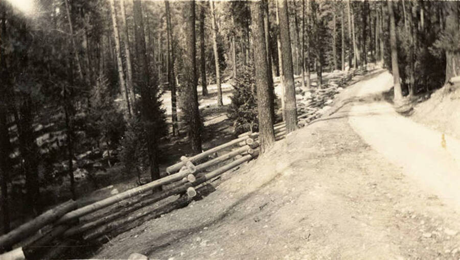 Photo of a road and log fence leading through the woods. Writing under the photo reads: 'Picnic Ground'.