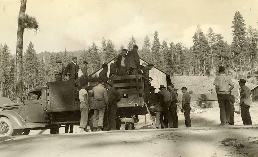 A truckload of CCC men returning to their CCC camp after being away for 26 days fighting fires. Writing under the photo reads: 'Back from fighting fire for 26 days'.