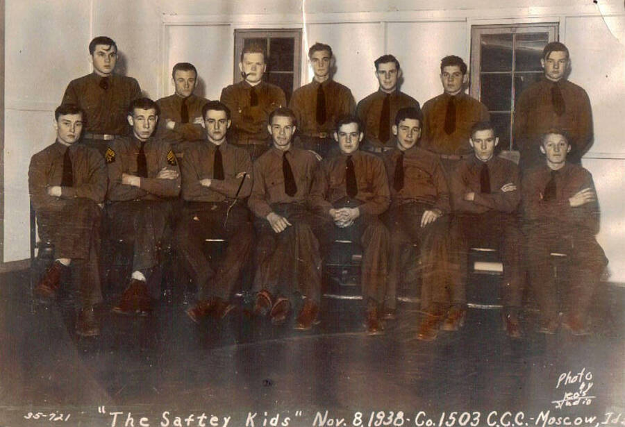 Group portrait of 'The Safety Kids' a group of CCC enrollees. Writing on the photo reads: ''The Saftey Kids' Nov. 8, 1938 - Co. 1503 CCC - Moscow, Ida[ho] Photo by Leo's Studio'. There is an arrow under the photo labeled 'John'.