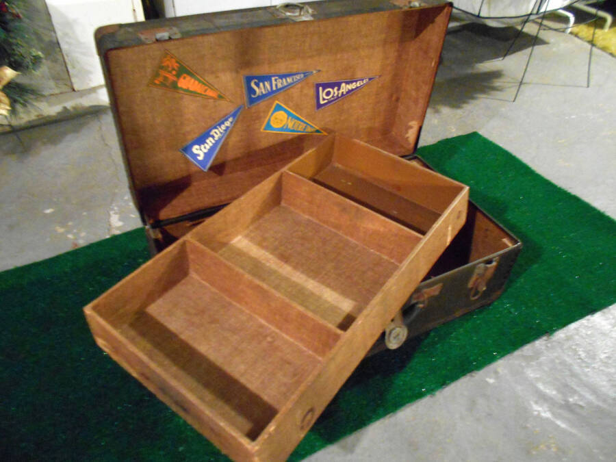 Interior of a travelling trunk that belongs to Johnny 'Duck' Pollauf. There are flags inside the trunk that read: 'San Diego', 'San Francisco', 'Los Angeles, 'Notre Dame.'