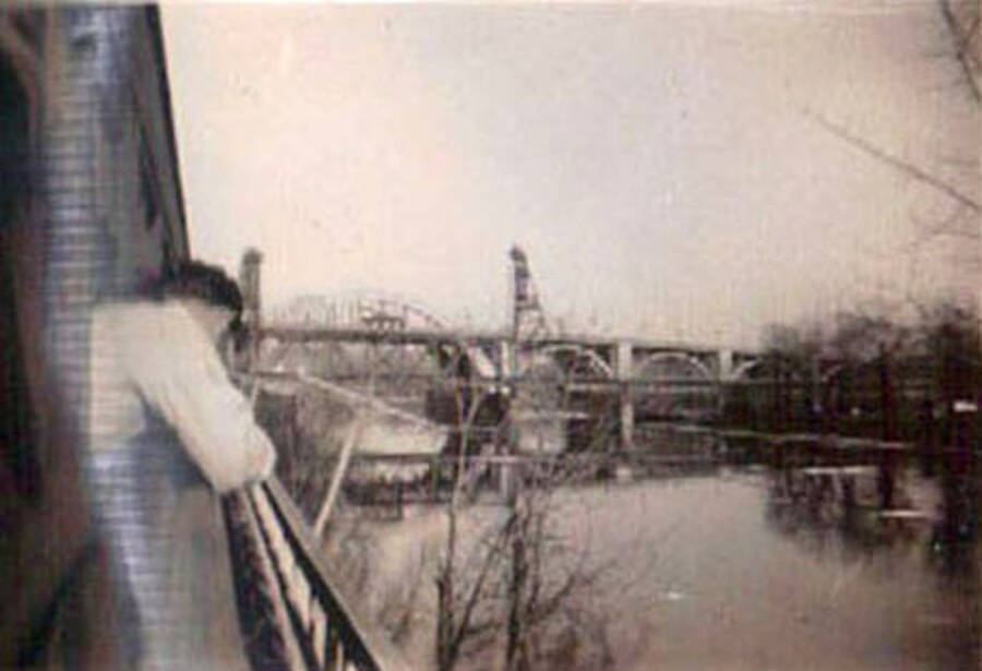 A CCC man leans out of a train to get a view of a nearby river and bridge. Label on the album page reads: 'John's friends Idaho'.