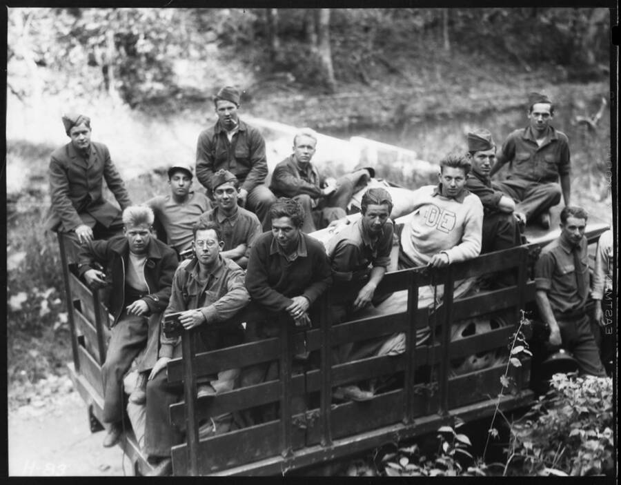 Truckful of CCC enrollees on their way from Idaho to Andersonville, Tennessee. Most of the men are wearing uniforms, one man is wearing a sweater with the letters 'DE' on it.