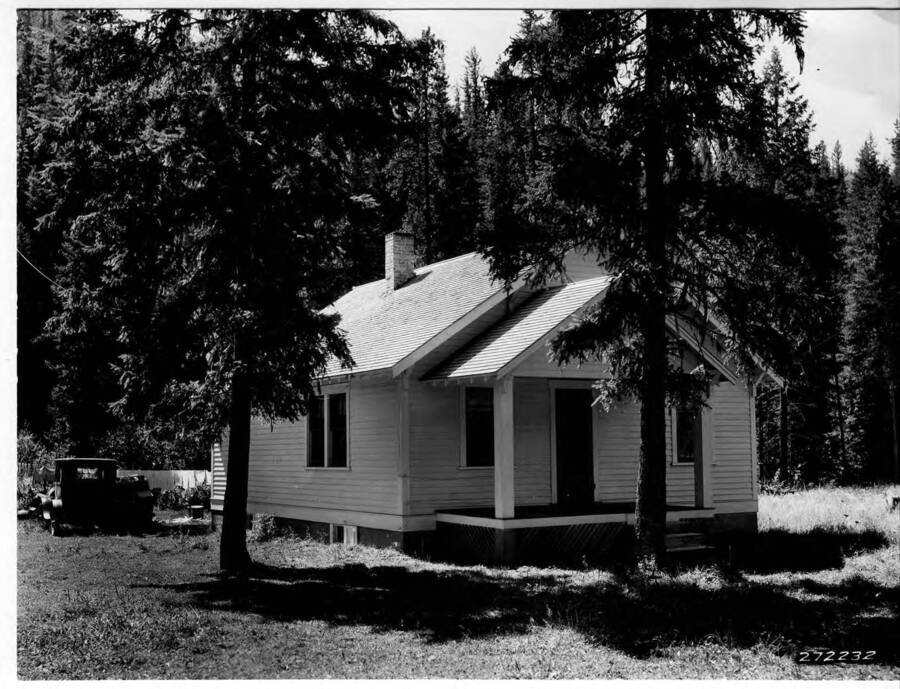 Building at the Powell Ranger Station before the CCC was there. There is a truck parked next to the building and two trees in the foreground.