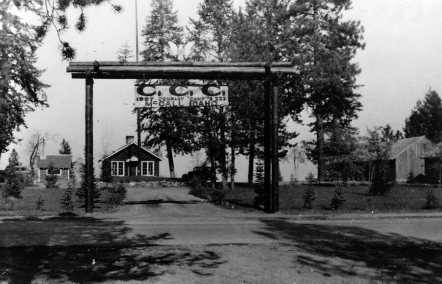Sign over the entrance to CCC Camp S-223. Writing on the sign reads: 'CCC 1907 Company Camp S-223 McCall Idaho'. Writing under the photo reads: '1850.0002. CCC Camp S-223, McCall, Idaho, 1935, Main Gate 1935/36 Author: David Lyon Print (Negetive in '1850 D. Lyon Nagatives') Ilford'.
