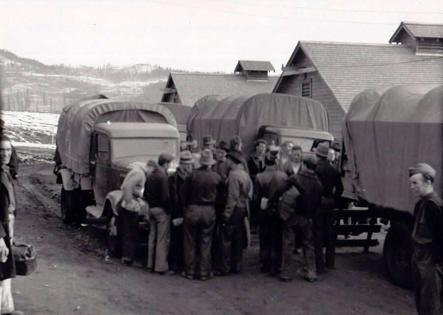 A group of men and trucks getting ready to head out to Priest River for an outing. Some CCC men went home if they lived nearby. Taken in the spring at Camp Kalispell Bay, F-142 of Company 1994 near Priest Lake, Idaho.
