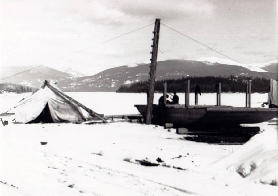Barge being repaired on the beach at Kalispell Bay in front of Camp F-142, Company 1994. The lake was frozen over.