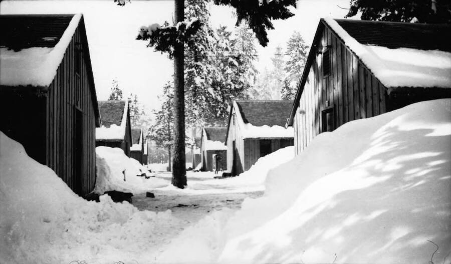 Camp barracks covered in snow in McCall, Idaho. Writing beneath the photo reads: 'Photo No. 1850.0094. Barracks, S-223, McCall, 1935-36'