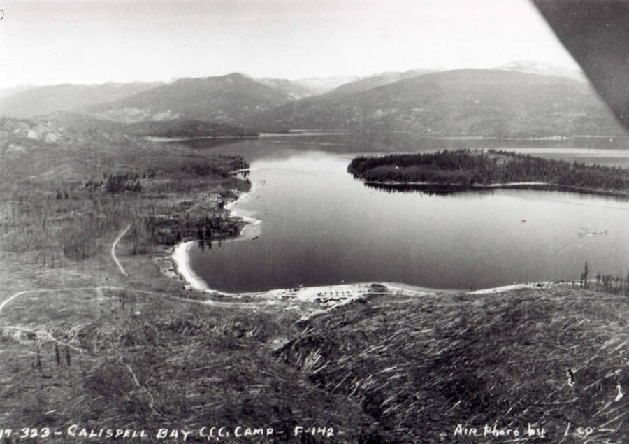 Aerial view of Camp Kalispell Bay, F-142, where Company 1994 is stationed, on Priest Lake, Idaho. Writing on the photo reads: ' Calispell Bay CCC Camp - F-142 Air photo by Leo'