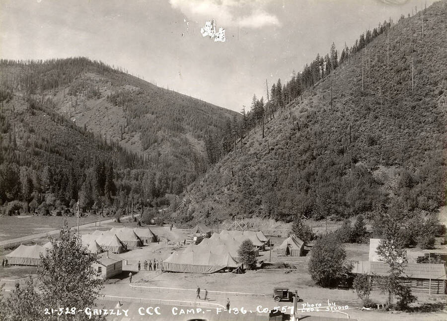 View of Grizzly Camp and the surrounding scenery. Writing on the photo reads: '21-528 Grizzly CCC Camp F-136 Company 557 Photo by Leo's Studio'.