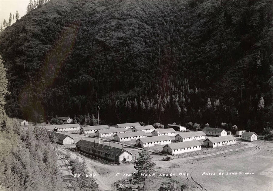 View of Wolf Lodge Bay CCC Camp and hillside in background. Writing on the photo reads: '25-644 F-182 Wolf Lodge Bay photo by Leo's Studio'.