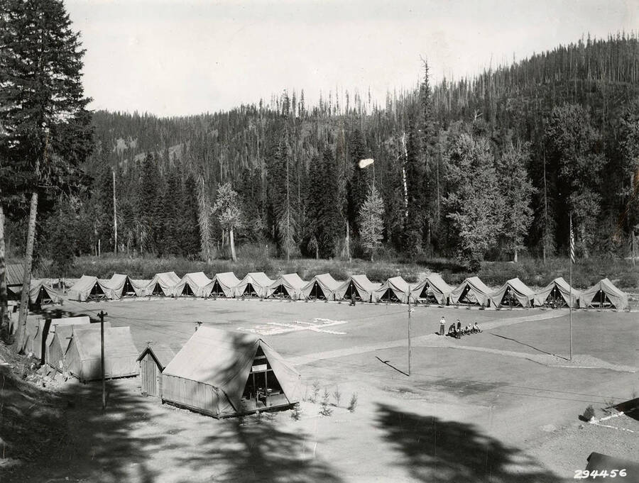 A view of the tent barracks of Rock City CCC Camp. A geoglyph in the center of the clearing reads: 'F-153'. Back of photo reads: 'Rock City CCC Camp Swan October 1934'.