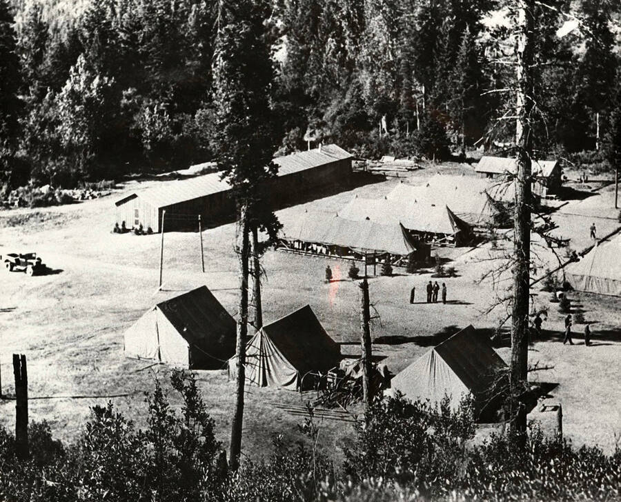 A view of Prichard CCC Camp F-30, renamed from Harry Marsh CCC Camp. Camp is located in the Coeur d'Alene National Forest on the Coeur d'Alene River. Back of photo reads: 'Museum of North Idaho P.O. box 812 Coeur d'Alene, Idaho 83814 Pritchard (Harry Marsh) CCC Camp F-30 on Coeur d'Alene River 1933. Slide Forest Service.'