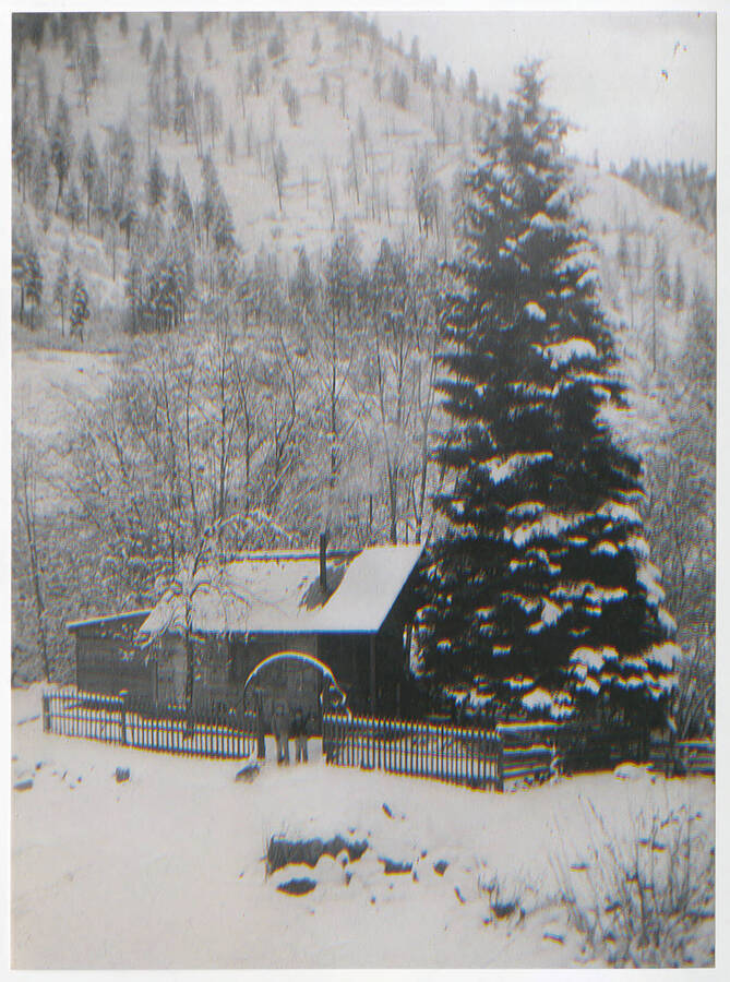 Far shot of two young Busch children, Michael and Pete (aged seven and six), waving from the gate of their family cabin at  Jack Howard Ranch near Elk Horn Creek and Salmon River Road in the winter of 1940-41. The Busch's lived here from summer 1940 to spring 1941.