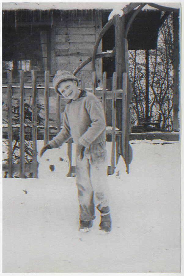 Young Michael Busch poses by a snowman in front of the gate of his family's cabin at Elk Horn Creek.
