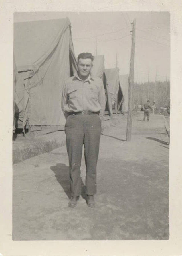 Pat' Saddler was the Fire boss on the Avery fire. He can be seen standing in front of a line of tents. The back of the photograph reads: ''Pat' Saddler - my boss on the fire in Avery.'
