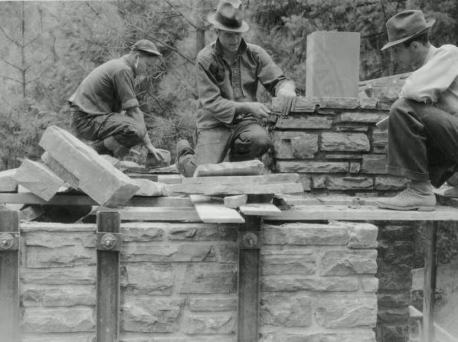 Three men installing a basalt rock incinerator at Rocky Point in Heyburn State Park