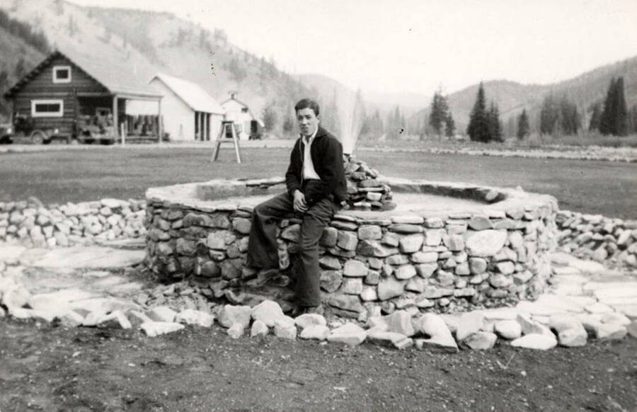 Portrait of Art Moore sitting at a fountain near the Magee Ranger Station. Back of photo reads: 'Art Moore CCC Company 544 1935 Magee R.S.' Stamp reads: 'Nationally Known RAYS LaCrosse Wisconsin, Guaranteed Prints'.
