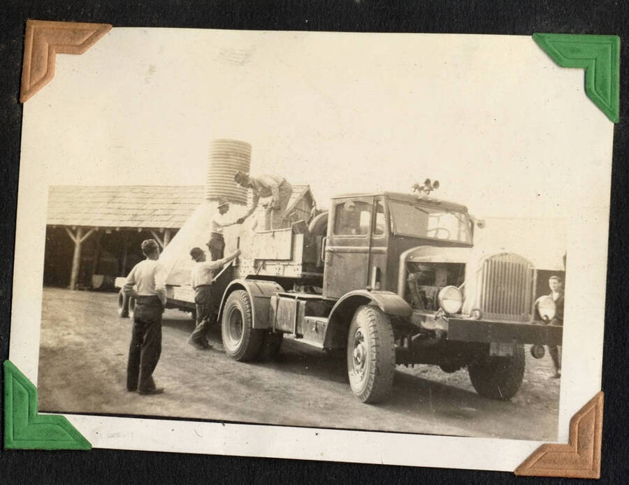 Four men with truck hauling a large loaded flatbed. SCS-1, C-1503. From the Paul Saft photographic album, SCS-1, C-1503, 1938-39, depicting camp life, taken mostly in the Moscow, Lewiston, Robinson Lake areas.