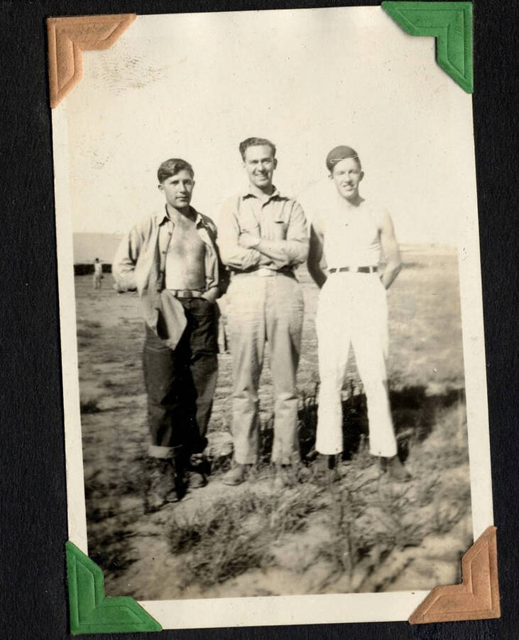 Three men, posed in field, center man in uniform, SCS-1, C-1503. From the Paul Saft photographic album, SCS-1, C-1503, 1938-39, depicting camp life, taken mostly in the Moscow, Lewiston, Robinson Lake areas.