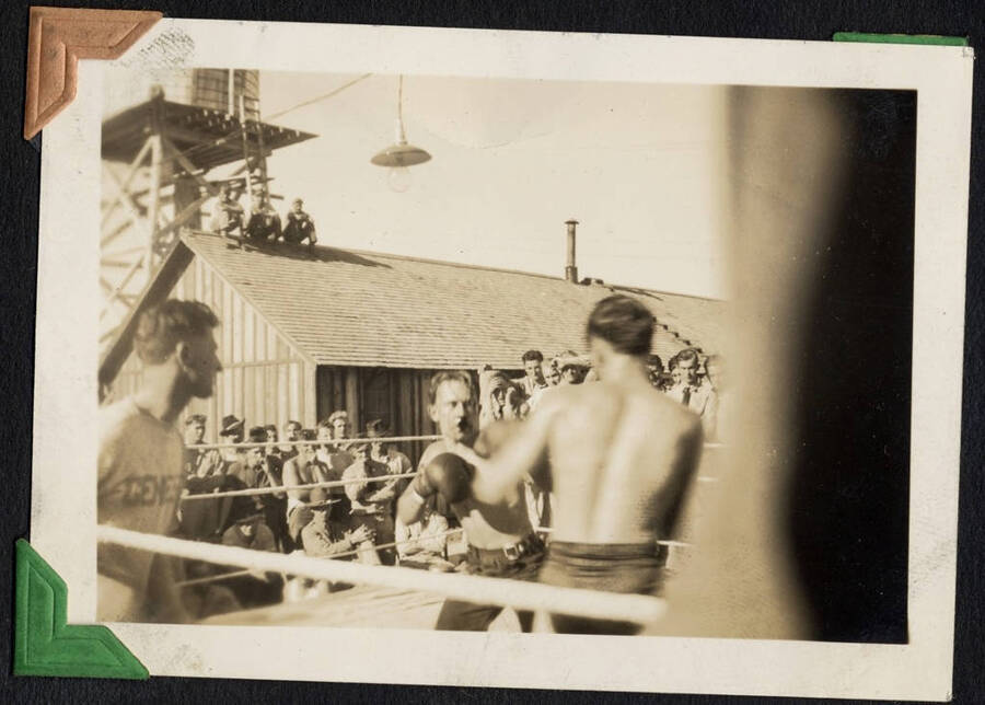 Boxers, a referee, and spectators in outdoor boxing rink. SCS-01,C-1503. From the Paul Saft photographic album, SCS-1, C-1503, 1938-39, depicting camp life, taken mostly in the Moscow, Lewiston, Robinson Lake areas.