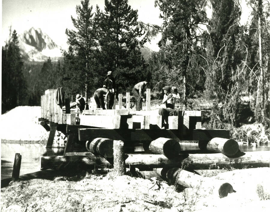 Work crew building a wooden bridge across river. Possibly Shafer Butte. back of photo reads: 'Civlian Conservation Corps, 35-EC-1A-1 National Archives