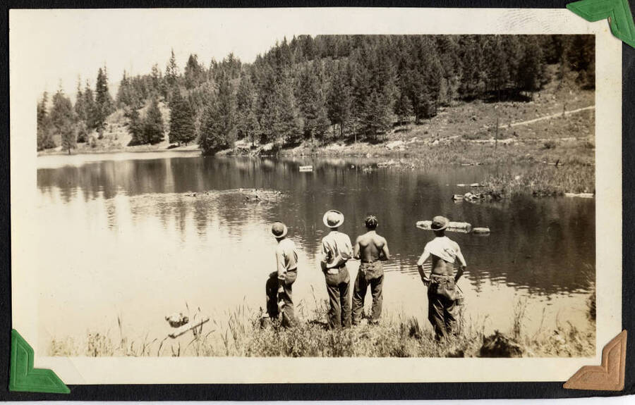 Four men standing on shore of lake, SCS-1, C-1503. From the Paul Saft photographic album, SCS-1, C-1503, 1938-39, depicting camp life, taken mostly in the Moscow, Lewiston, Robinson Lake areas.