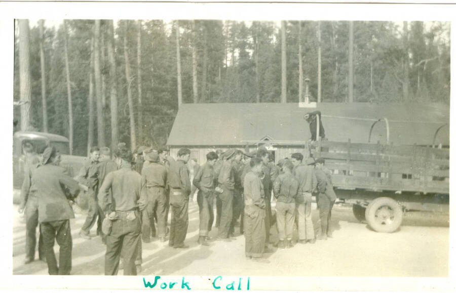 Picture from photo album of a work crew waiting to board trucks. Handwritten caption: 'Work Call'. This is likely to be located at Camp Creek, South Fork of the Salmon River, which built Krassel Ranger Station.