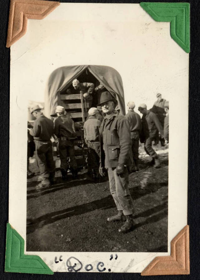 Man in foreground, captioned 'Doc'. Truck and other men in background. SCS-1, C-1503. From the Paul Saft photographic album, SCS-1, C-1503, 1938-39, depicting camp life, taken mostly in the Moscow, Lewiston, Robinson Lake areas.