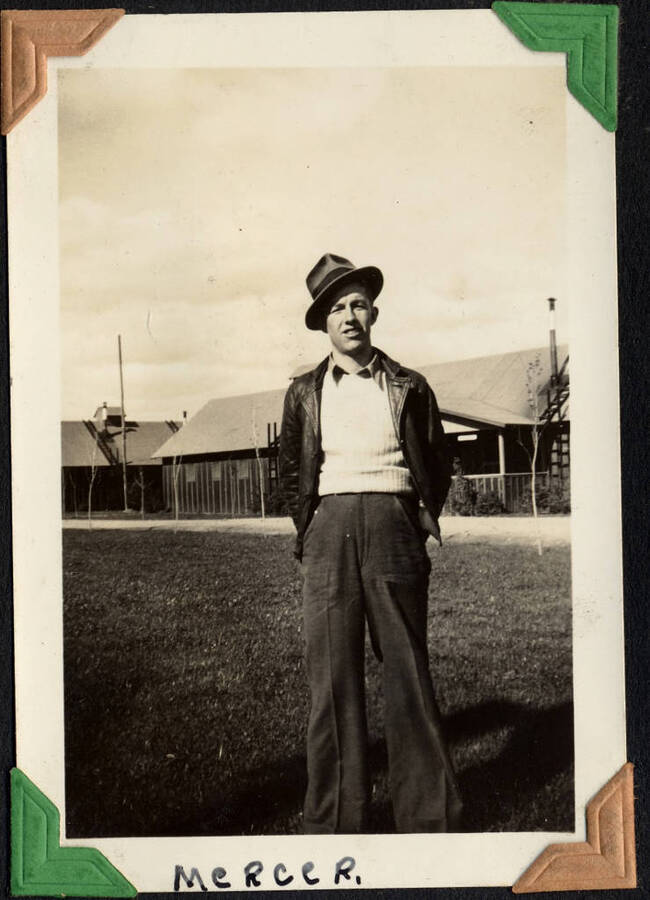 Man standing in front of camp buildings, captioned 'Mercer'. SCS-1, C-1503. From the Paul Saft photographic album, SCS-1, C-1503, 1938-39, depicting camp life, taken mostly in the Moscow, Lewiston, Robinson Lake areas.