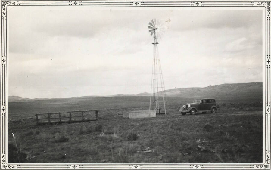 Crossing bridge, windmill and car in field, Fort Hall camp
