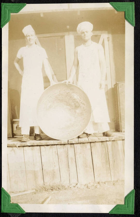 Two camp cooks posing with large pan. SCS-1, C-1503, Moscow, Idaho. From the Paul Saft photographic album, SCS-1, C-1503, 1938-39, depicting camp life, taken mostly in the Moscow, Lewiston, Robinson Lake areas.