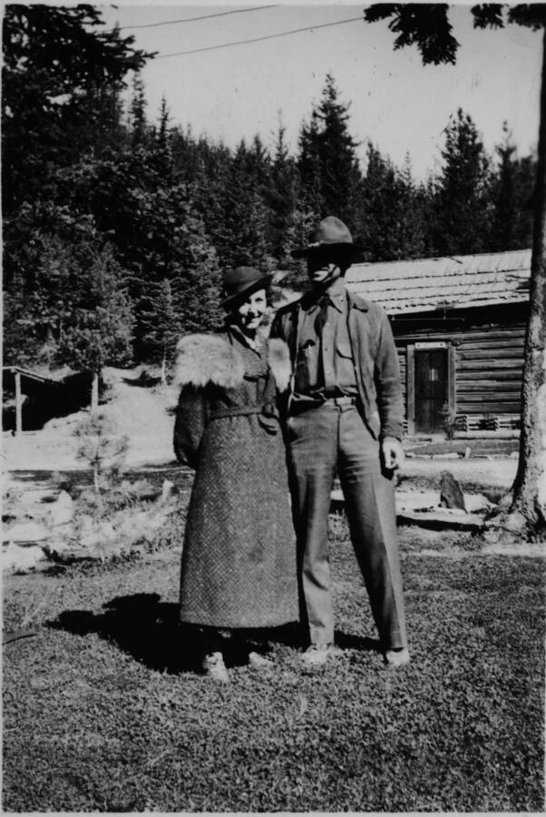 Picture of Captain and Mrs. Lubbin standing in the camp with a wood building in the background.