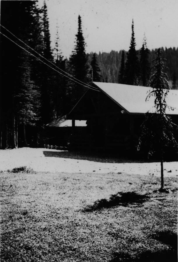 Picture of a building with open area in front and forest behind.