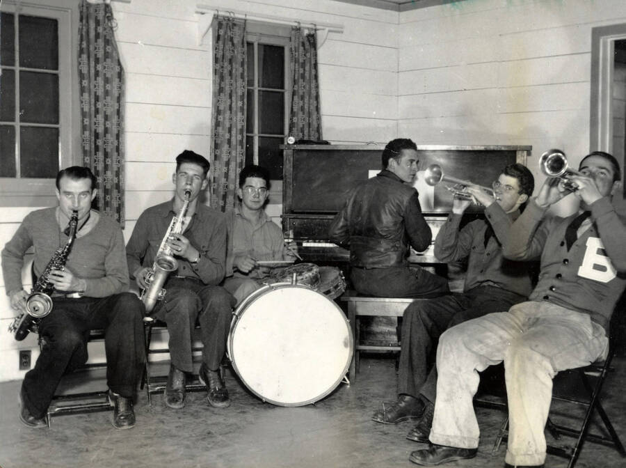 Six young men play instruments (saxophone, drums, piano, trumpet) as the Camp Heyburn State Park band.