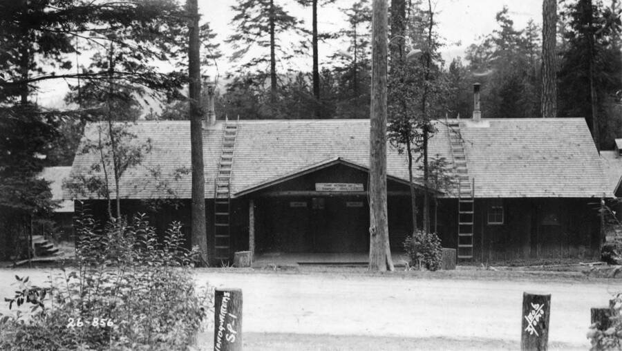Exterior view of headquarters building at Camp Heyburn. The sign above the door says 'Camp Heyburn SP-1, Company 1955 CCC'. The sign to the left beneath it says 'Office' and the other says 'Supply'.