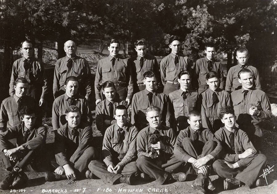 Group portrait of CCC men at Hayden Creek CCC Camp. Writing on the photo reads: 'Barracks #7 F-180 Hayden Creek Leo's Studio'.