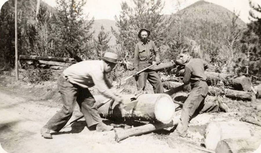Two CCC men using a crosscut saw to saw a log while a third man watches. Back of photo reads: ''Inky' Ingerlund (left) USFS, Pappy Dejarnette Cloverport (KY), Paul Newby, Louisville (KY) Magee 1935'.