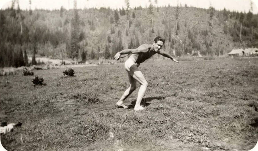 Unclothed man prepared to throw a discus and poses for the camera. Back of photo reads: 'Magee 1935'.