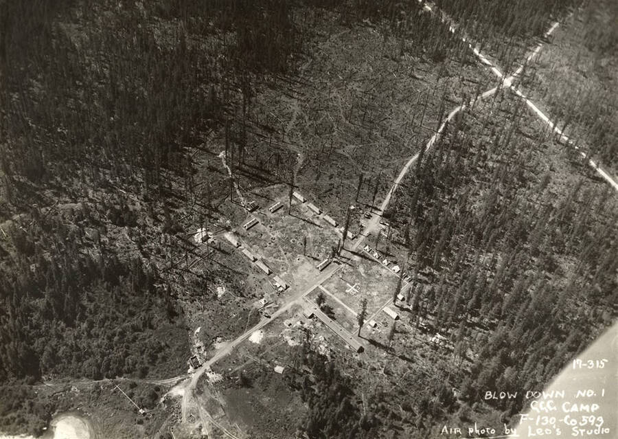 Aerial view of Blow Down 1 CCC Camp, F-130. Note geoglyph reading 'F-130' in the center of the field. Writing on the photo reads: 'Blow Down Number 1CCC Camp F-130 Company 593 Air photo by Leo's Studio'.