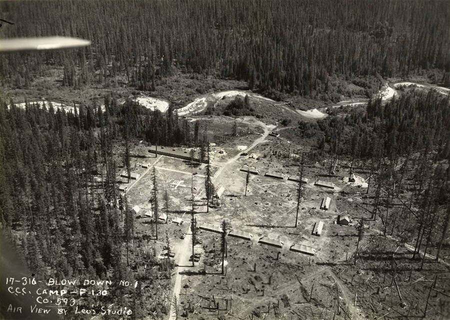 Aerial view of Blow Down 1 CCC Camp, F-130. Note geoglyph reading 'F-130' in the center of the field. Writing on the photo reads: 'Blow Down Number 1 CCC Camp F-130 Company 593 Air view by Leo's Studio'.