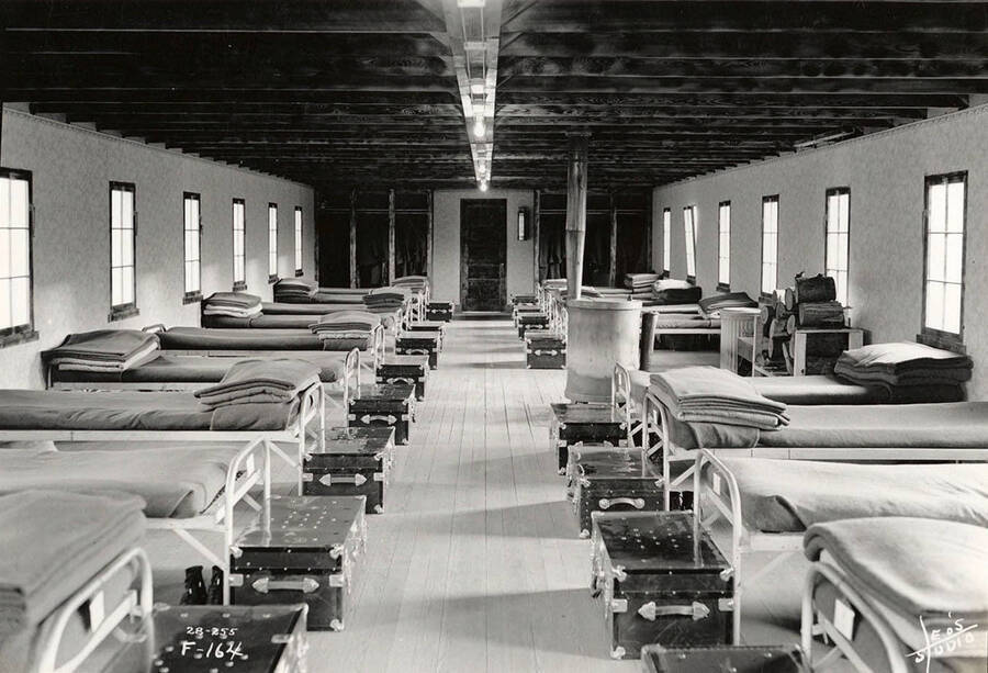 Interior view of a dormitory at Four Corners CCC Camp, F-164. Writing on the photo reads: 'F-164 Leo's Studio'. Back of photo reads: 'Four Corners Priest River'.