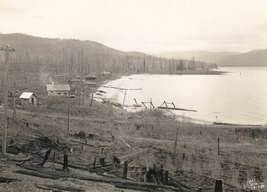 View of Kalispell Bay and a few outbuildings of the CCC Camp stationed there, F-142. Writing on the photo reads: 'Leo's Studio'. Back of photo reads: 'Kalispell Bay'